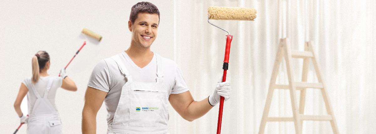 Male painter with a paint roller posing and a female painter pai